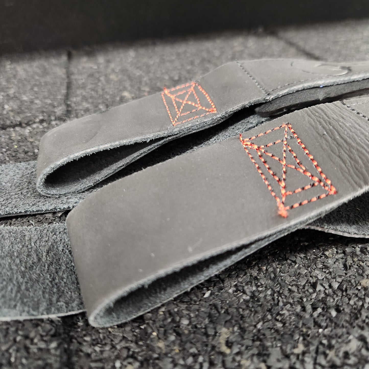 Close up shot of red, box stitching on black leather weightlifting straps by White Lion Athletics.