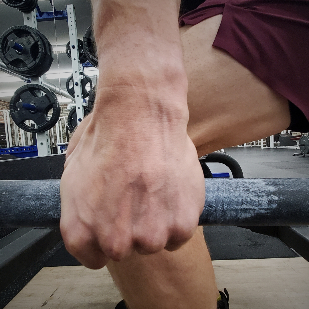 Gym chalk by White Lion Athletics being used on hands while holding onto to trap bar handles.