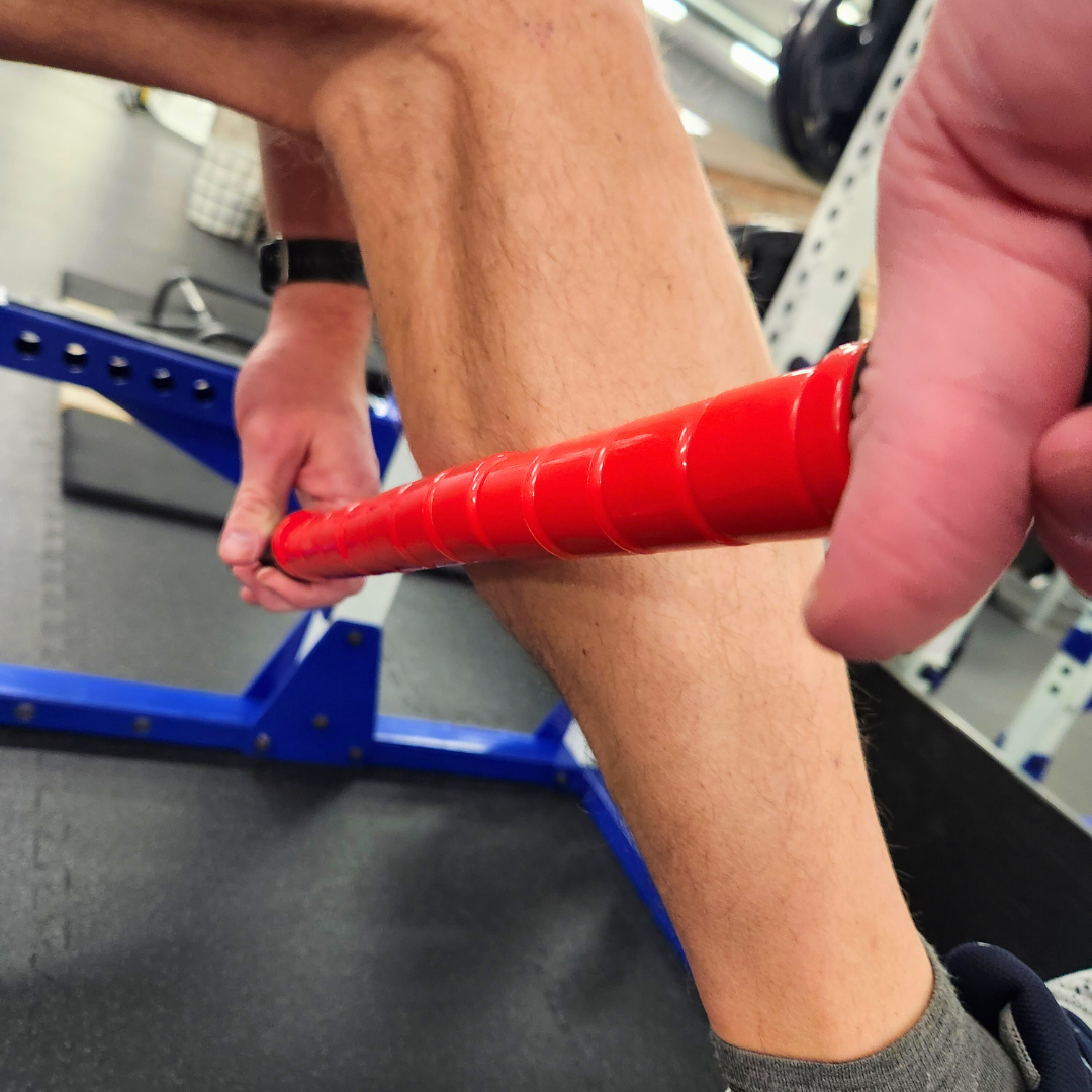 Male athlete using White Lion Athletics Big Red Massage stick on their calf. 