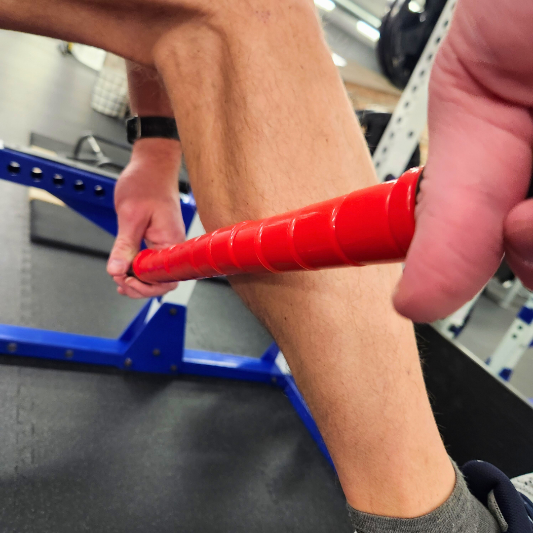 Male athlete using White Lion Athletics Big Red Massage stick on their calf.