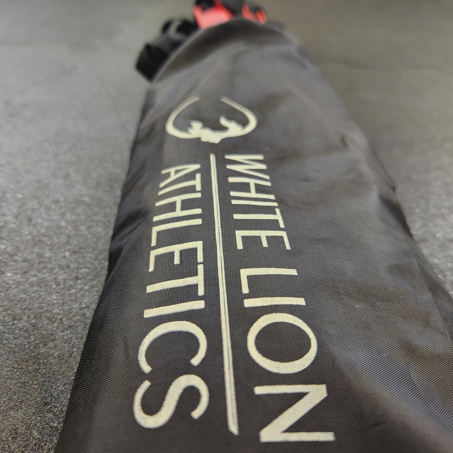 Close- up photo of 6 meter agility ladder by White Lion Athletics. Red rungs with heavy duty black nylon webbing and black, drawstring carrying bag.