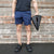 A person is demonstrating how to carry steel squat wedges made by White Lion Athletics using the handle inserts on the back of the wedge