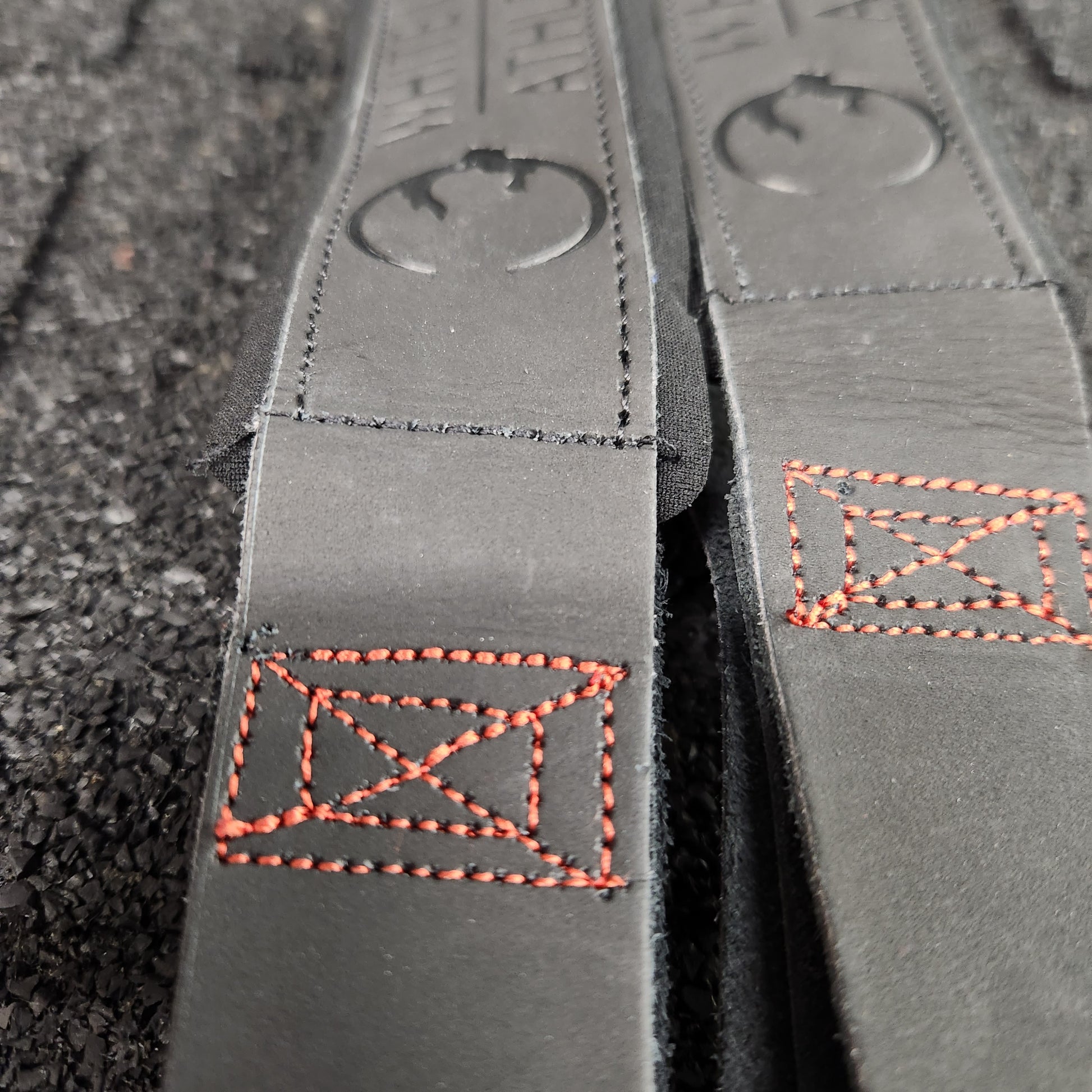Close-up shot of embossed logo on black leather weightlifting straps  by White Lion Athletics.