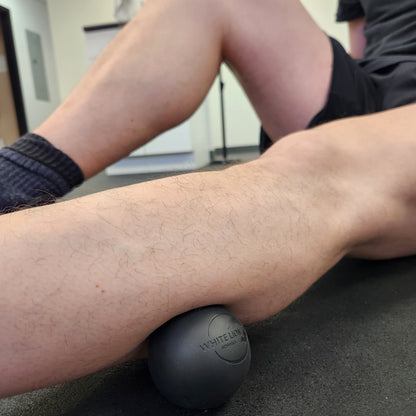 Lacrosse ball being used on lower leg for self-massage 