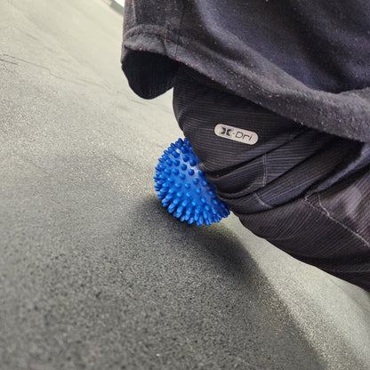 Spiky ball being used for self-massage on glutes.