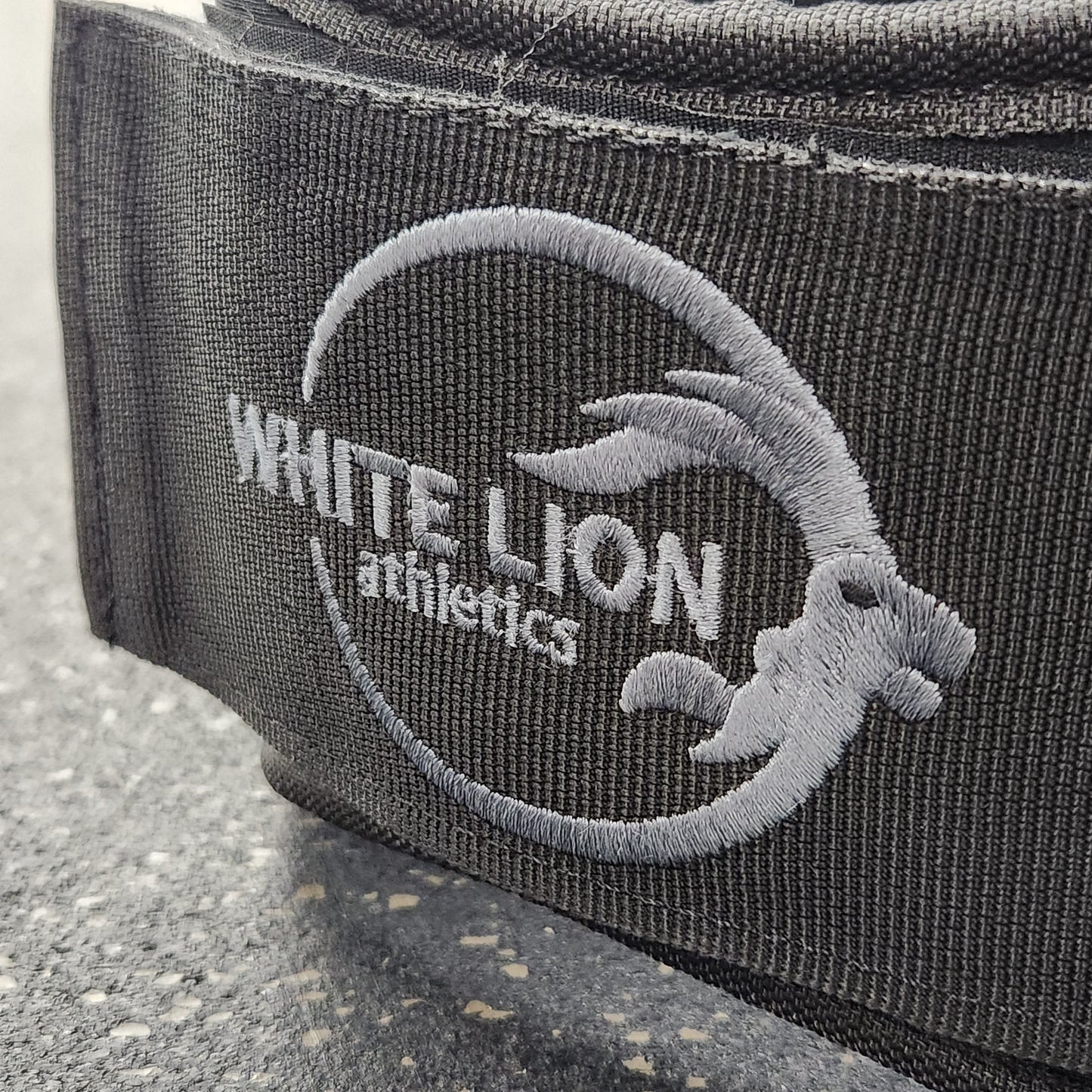 Close-up shot of embroidered logo on Weightlifting Belt | BLK MAX  5" Nylon Lifting Belt - White Lion Athletics.