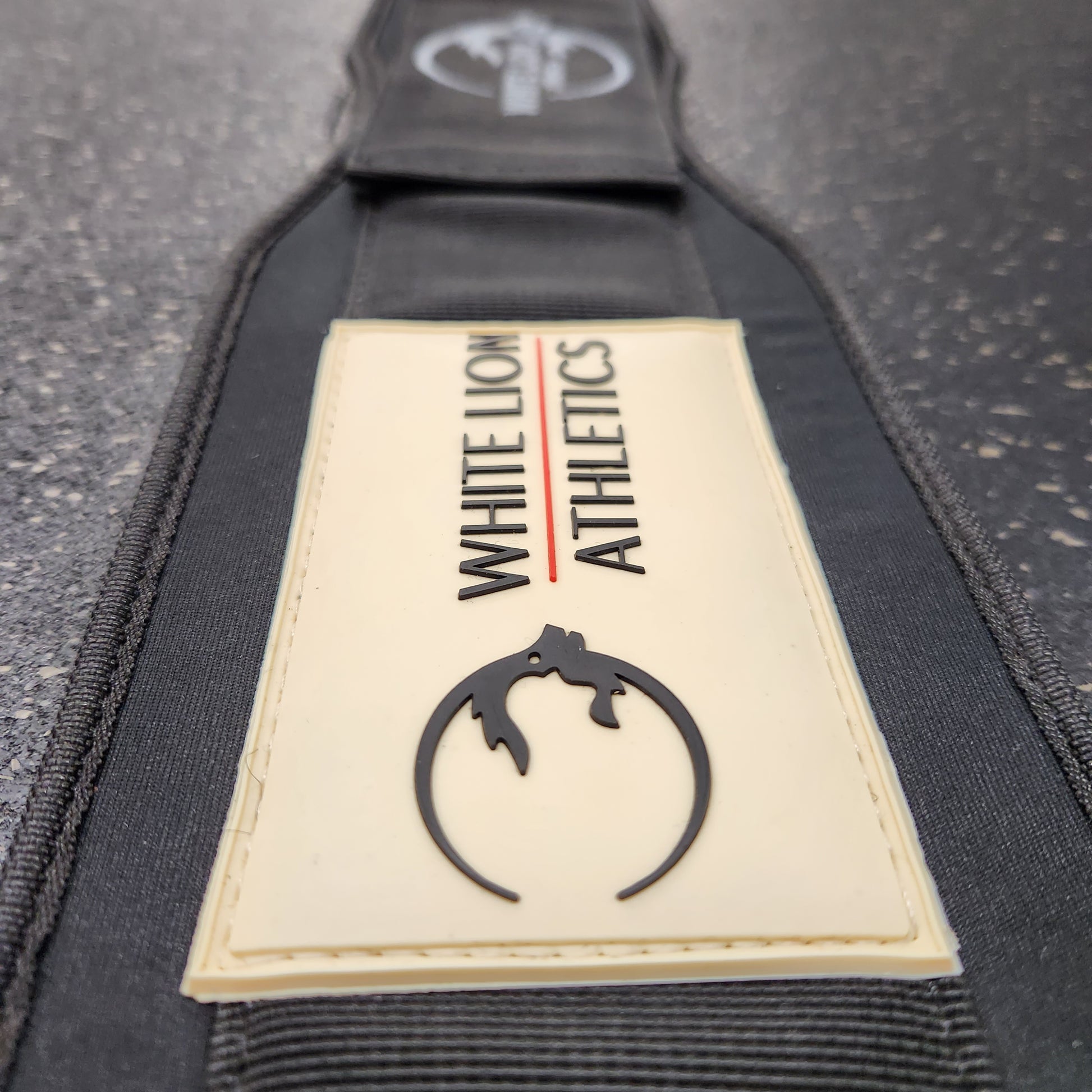 Close-up shot of rubber logo with embrodiered logo in background of Weightlifting Belt | BLK MAX  5" Nylon Lifting Belt - White Lion Athletics.