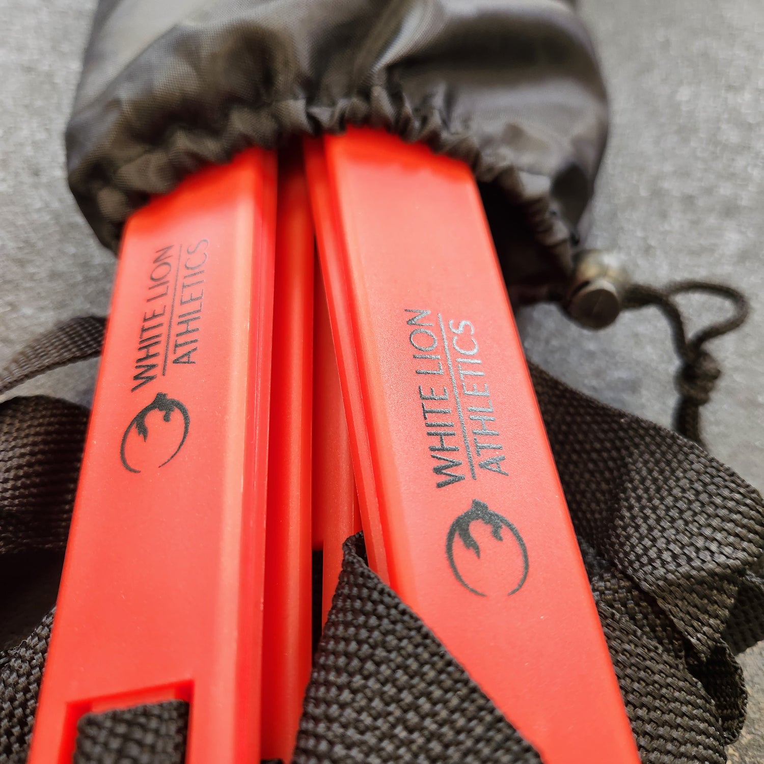Close-up photot of the black logos on the red rungs of a 6 meter agility ladder by White Lion Athletics. Ladder is pictured in it's black drawstring carrybag.