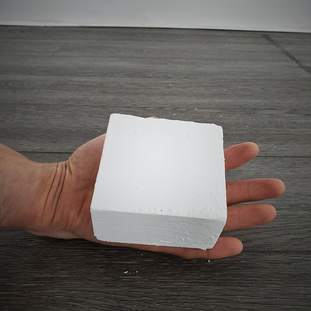Single block of gym chalk being held in athletes hand to show how large it is.