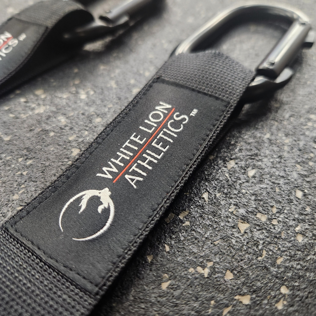 Close-up shot of the fabric logos stitched onto the White Lion Athletics competition straps for gymnastics rings.