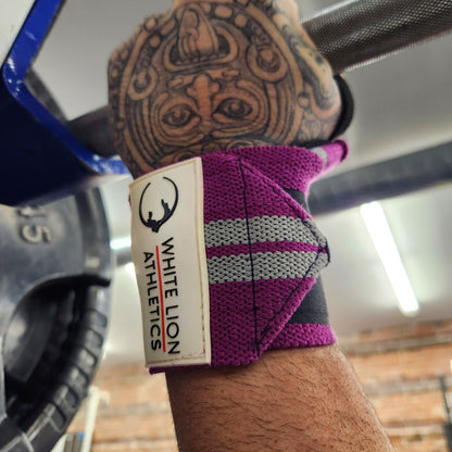 A close up shot of a  White Lion Athletics Purple with Grey stripes wristwraps on a male athletie's left wrist while bench pressing.