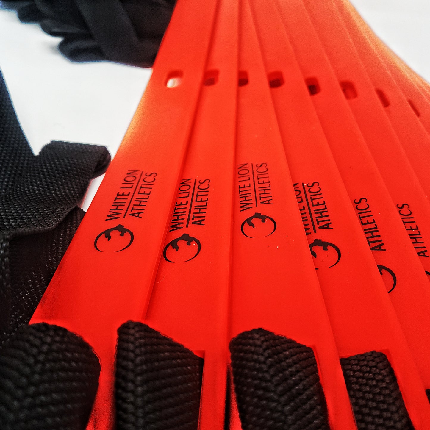 Close-up shot of the red rungs on the White Lion Athletics 6 meter agility ladder.  The black White Lion Athletics  logo is featured on  each rung of the Agility Ladder .